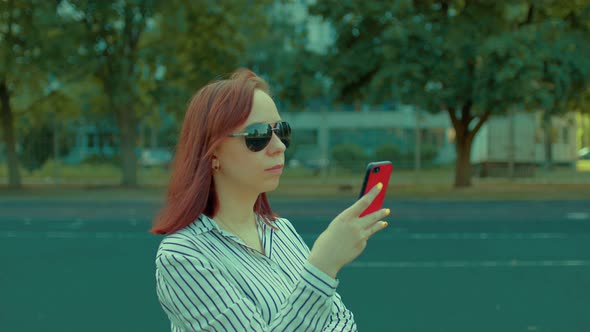 Young Woman in Sunglasses with Mobile Phone on Street in Summertime