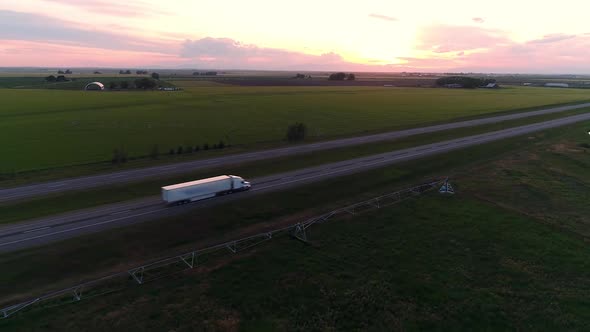 Semi Truck driving on freeway into the distance during sunset