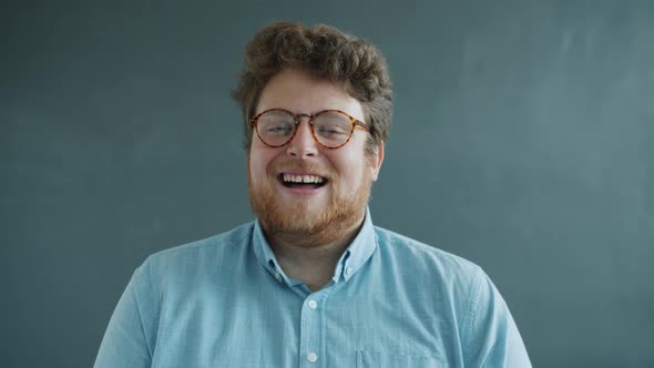 Portrait of Joyful Man Laughing Looking at Camera Then Making Funny Faces on Gray Background