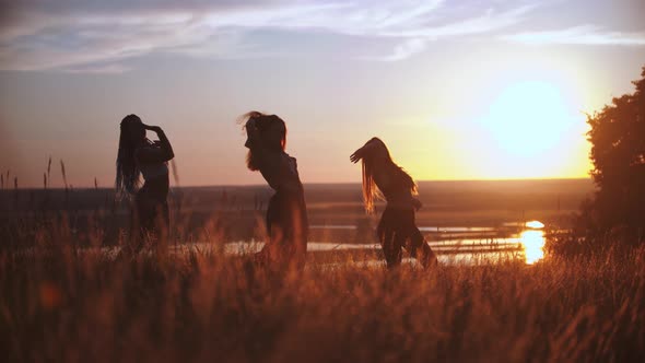 Three Young Women Doing Aerobic Dance on Sunset Field