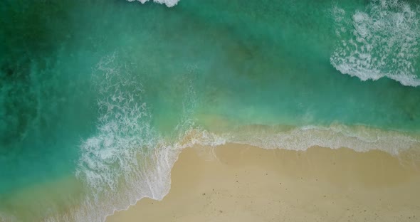 Daytime overhead abstract shot of a white sand paradise beach and aqua blue ocean background in 4K