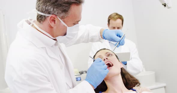 Dentist examining a female patient with tools