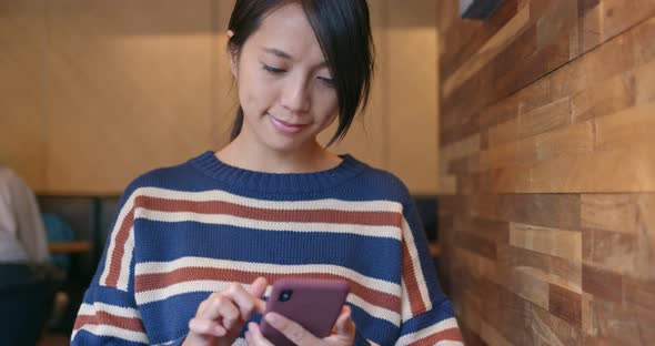 Woman work on cellphone inside coffee shop