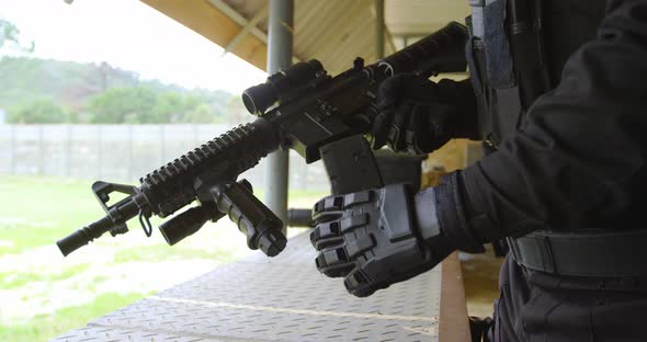 Mid section of young military soldier loading rifle magazine during military training 4k