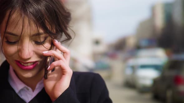 Attractive Young Woman Talking Smartphone During Walks in City Street