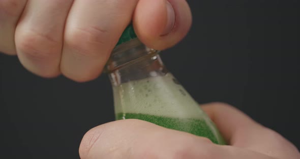 Man Opens Coke Bottle with Screw Top By Hands. Male Fingers Open Soda on Black Background