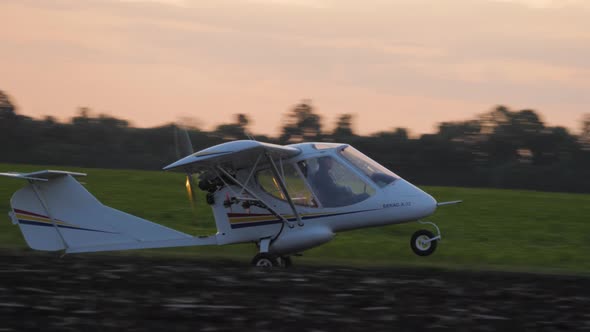 A Small Airplane Takes Off From a Field.at Sunrise