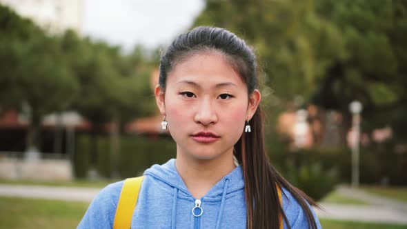 Portrait of Serious Teenager Student Standing at University Campus Looking at Camera