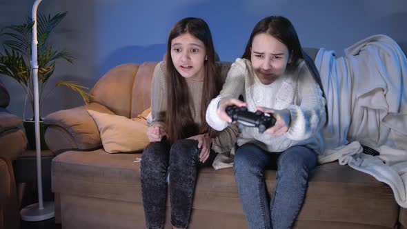 Laughing Excited Friends Sitting on Sofa at Night and Playing Video Games on Console