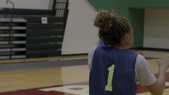 A female basketball player takes a pass and shoots the ball for a basket at practice in slow motion