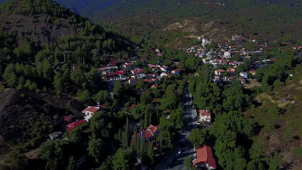 Aerial establishing shot of greek church and village nestled in vally