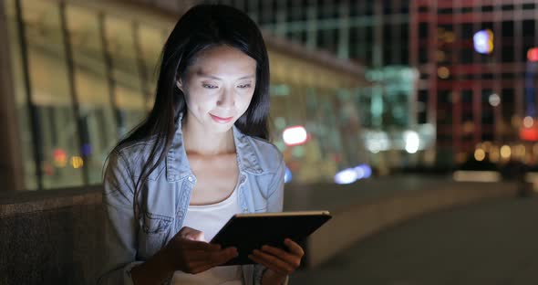 Woman looking on tablet computer at night