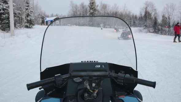 Shooting From the Driver's Seat Like a Column of Snowmobiles with Tourists Turns Onto a Forest Road