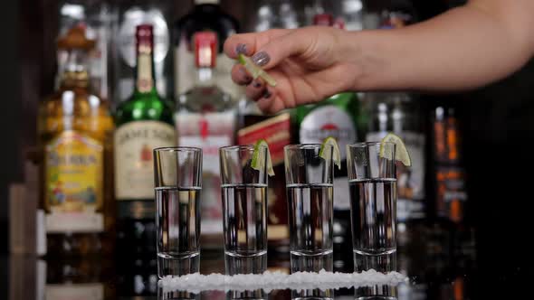 Bartender Decorating Shots of Tasty Tequila with Piece of Lime at Table in Bar