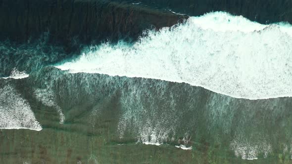 Dramatic seaside with white ocean waves splashing on colorful shore of tropical island with coral re