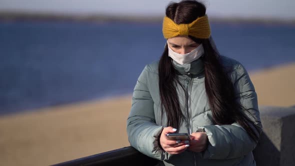 Young Woman Wearing a Mask Texting on the Smartphone