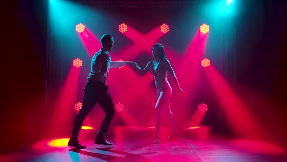 Young Couple Dancing Latin Music. Bachata, Merengue, Salsa. Shot in a Dark Studio with Neon Lights