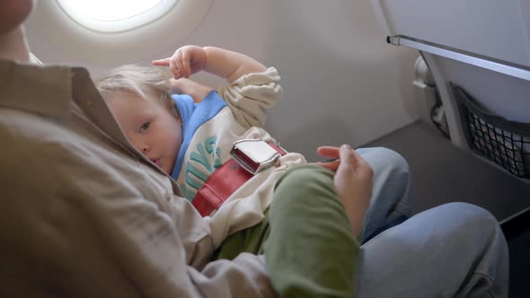 Baby Sleeping Inside Airplane Parent Masked Holding Infant Toddler Asleep While Flying in Economy