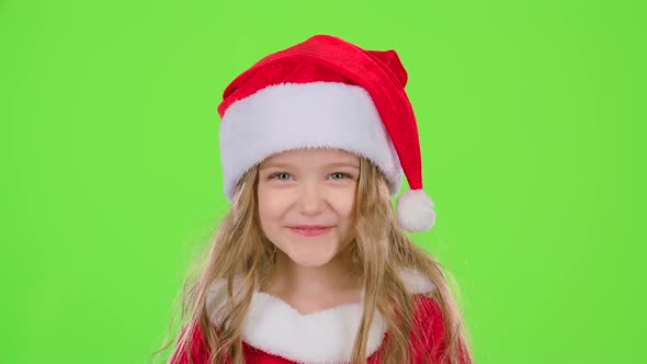 Baby in a Beautiful Suit and a Red New Year's Cap Smiles. Green Screen