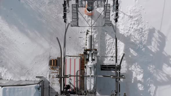 Aerial Top View of Ski Lift for Transportation Skiers on Snowy Ski Slope. Drone Flies Over Chair