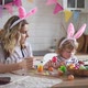 charming woman and her two-year-old son in bunny ears paint Easter eggs with paints - VideoHive Item for Sale