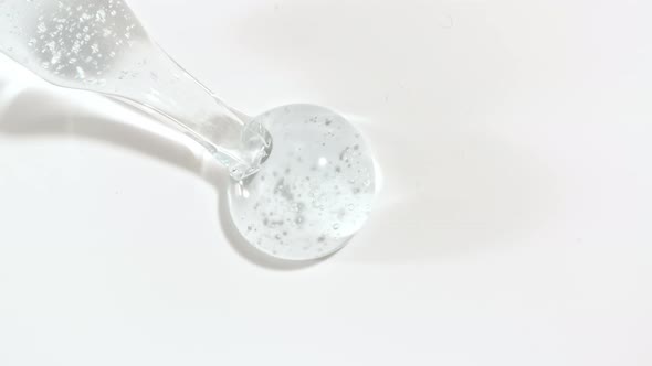 Macro Shot of Transparent Blue Cosmetic Fluid Gel Cream With Bubbles in Pipette Drips on a White
