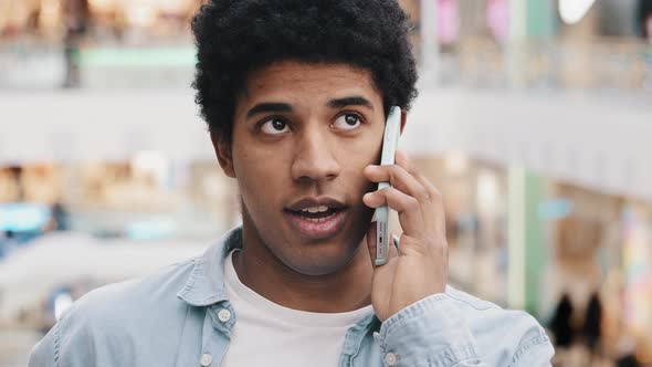 African American Millennial Man Standing Indoors in Office Corporate Space Talking on Smartphone
