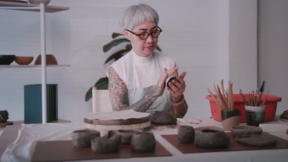 Asian elderly woman enjoying pottery work at home.