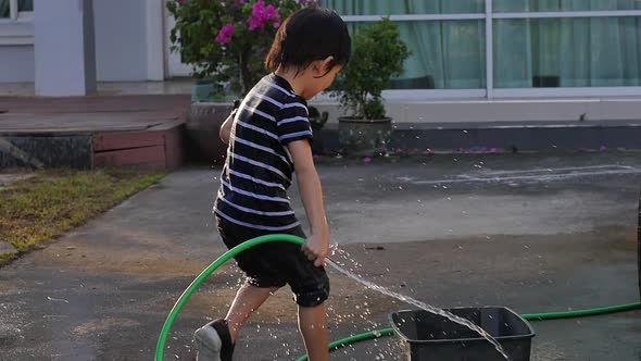 Cute Asian Boy Has Fun Playing In Water From A Hose Outdoors Slow Motion