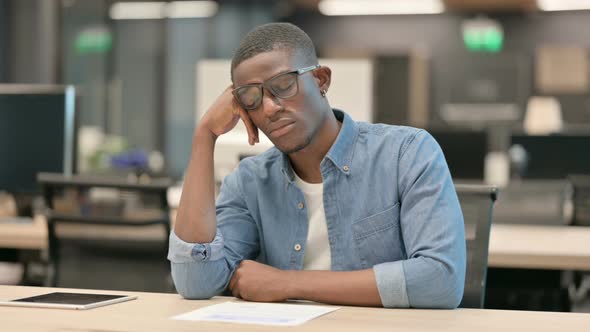 Tired Young African American Man Taking Nap While Sitting in Office