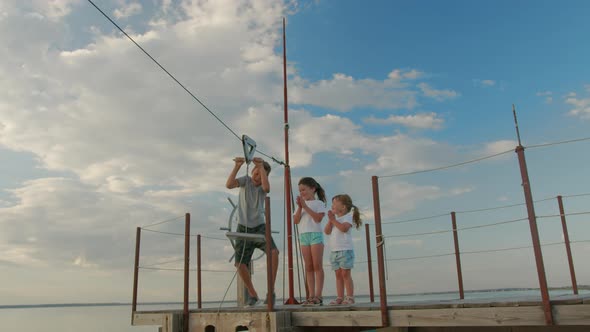 Three Children, Having Fun on a Swing in the Backyard on Sunset