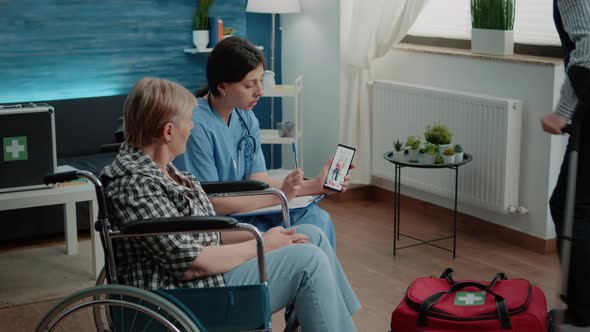 Old Invalid Woman and Nurse Talking to Doctor on Video Call