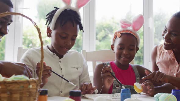 African american family painting easter eggs together at home