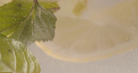 Slow Motion Macro Shot of a Lemon Slice in Water Bubbles Drinking Cold Lemonade