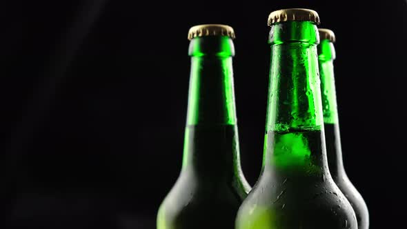 Three Green Glass Beer Bottles Spinning on a Black Background in the Dark