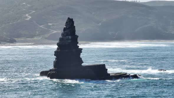 Aerial shot of a rock jutting out of the water in a beautiful bay on a sunny day