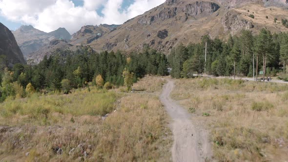 Car Drives Along Road in Autumn Forest Near Hotels in Azau Glade