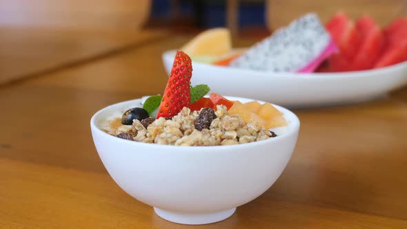 Granola Bowl with Yogurt Fresh Berries and Fruits on Wooden Table in Restaurant
