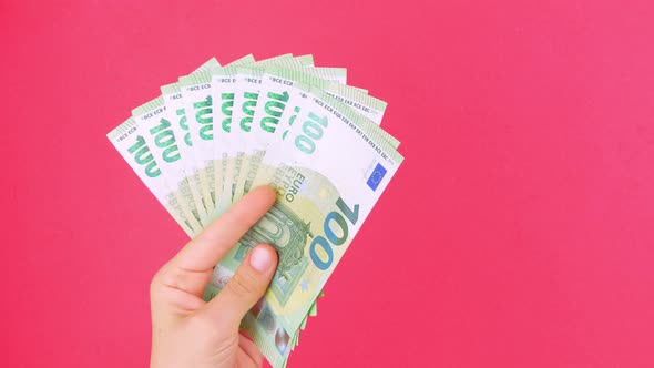 Hand in holds EURO money bills on pink color background. Counting cash european 100 banknote Casino