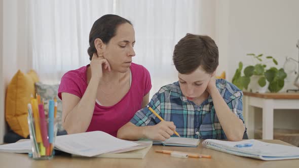 Mother helping her young son prepare homework during homeschooling