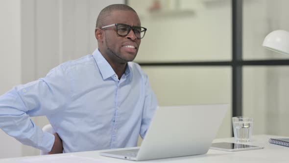 African Man Having Back Pain While Typing Laptop