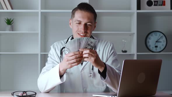 Portrait of Corrupted Male Medical Doctor Counting Money While Siitting at Workplace