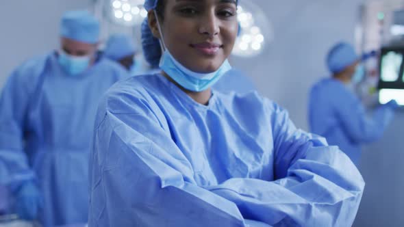 Portrait of mixed race female doctor standing in operating theatre smiling to camera