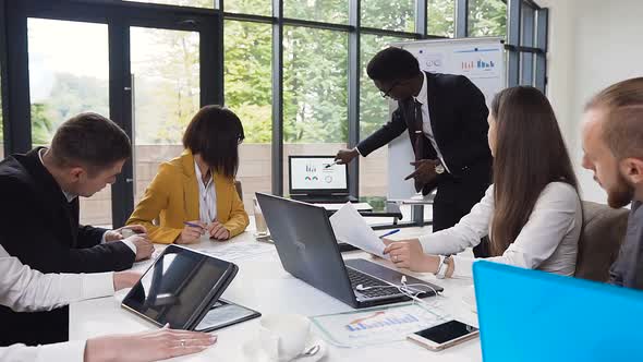 Entrepreneur is showing financial diagram on laptop on meeting business partners