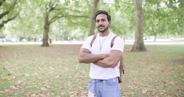 Portrait of confident man crossing arms in public park