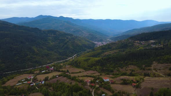 Steep green mountains, deep forest and mountain road, beautiful valley and village houses