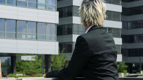 Business Middle Age Woman Looks Around - Company Building in the Background - Closeup