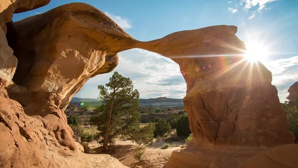 Sun rays shining in time lapse of arch in the desert