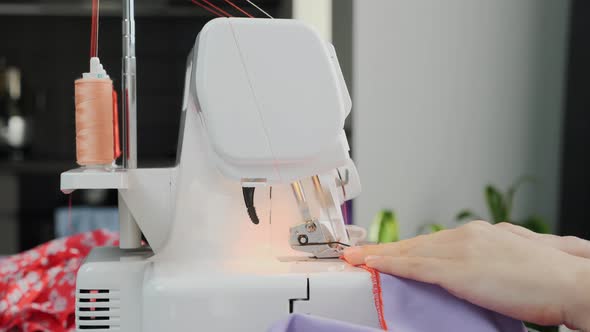 Woman sewing dress on sewing machine.