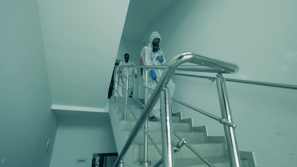 People in Hazmats Disinfect a Staircase.